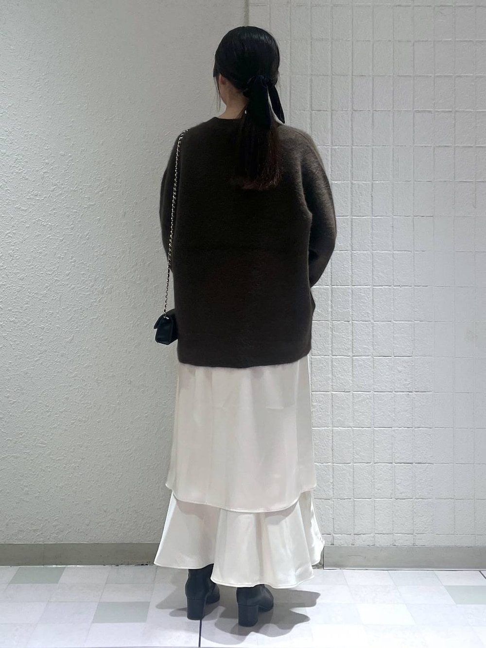 ブラウン系のカーディガン/ボレロ、ブラック系のブーツ、ホワイト系のワンピースを着用したレディースの秋コーディネートの3枚目の写真