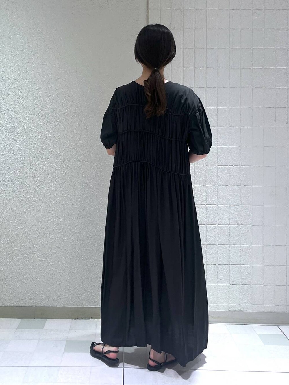 ホワイト系のハンドバッグ、ブラック系のサンダル、ブラック系のワンピースを着用したレディースの夏コーディネートの3枚目の写真