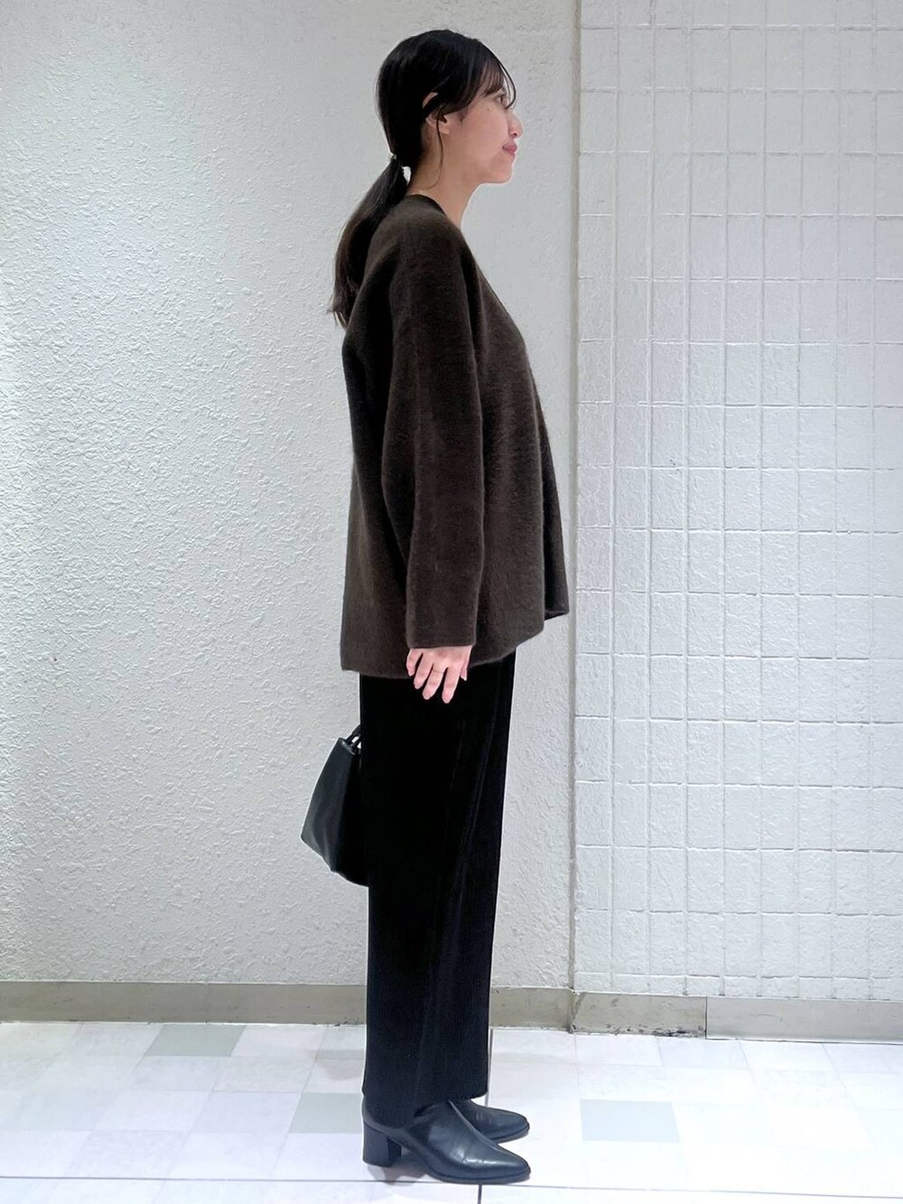 ブラウン系のカーディガン/ボレロ、ブラック系のブーツ、ブラック系のスカートを着用したレディースの秋コーディネートの2枚目の写真