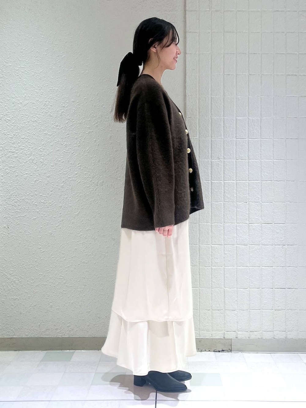 ブラウン系のカーディガン/ボレロ、ブラック系のブーツ、ホワイト系のワンピースを着用したレディースの秋コーディネートの2枚目の写真