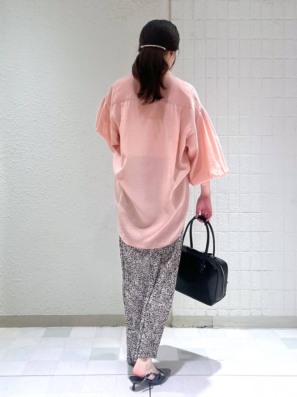 ピンク系のシャツ/ブラウス、ブラック系のボストンバッグ、ブラック系のパンプスを着用したレディースの春コーディネートの2枚目の写真