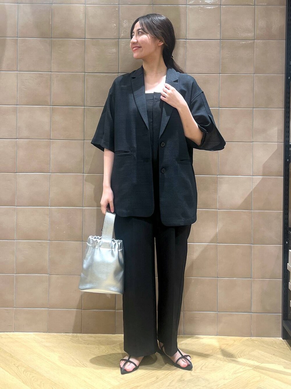 ブラック系のサロペット/オーバーオール、ブラック系のテーラードジャケット、ブラック系のサンダルを着用したレディースの春コーディネートの4枚目の写真