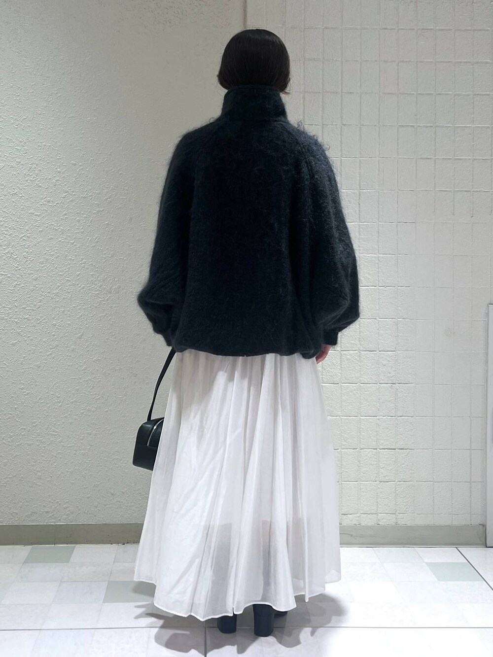 ブルー系のブルゾン、ブラック系のブーツ、ホワイト系のスカートを着用したレディースの冬コーディネートの2枚目の写真