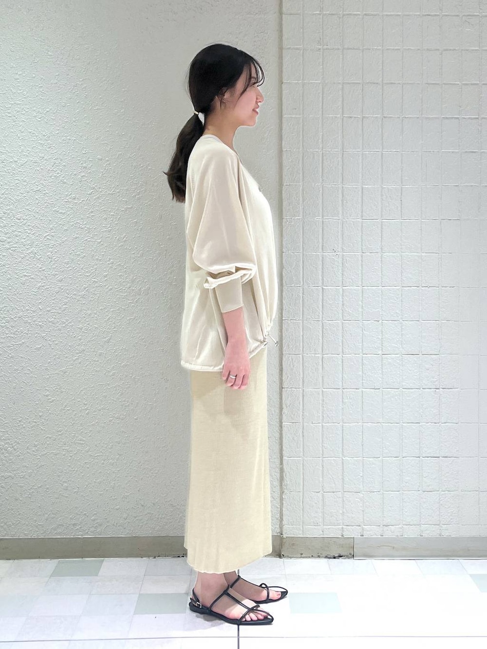 ゴールド系のスカート、ブラック系のサンダル、ホワイト系のタンクトップを着用したレディースの夏コーディネートの2枚目の写真