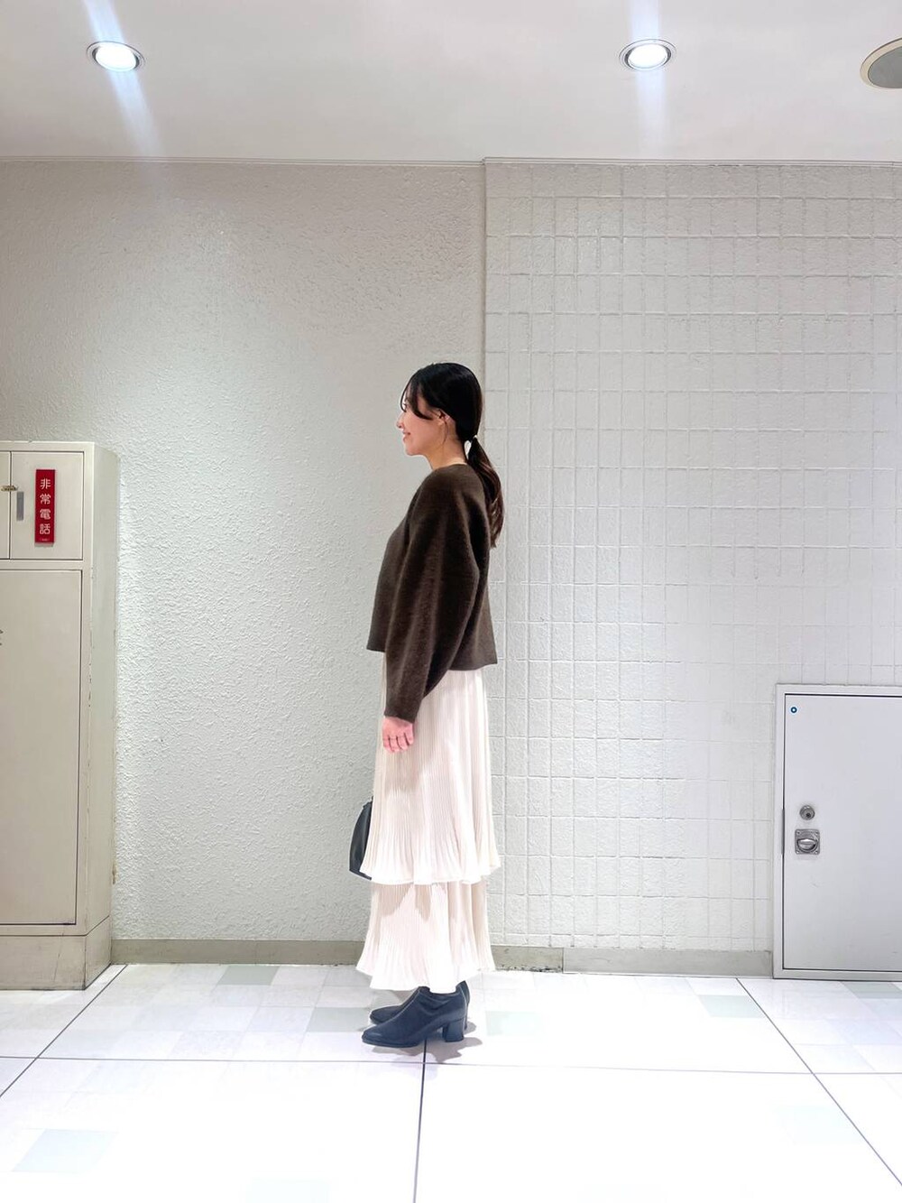 ブラック系のブーツ、ホワイト系のスカート、ブラウン系のカーディガン/ボレロを着用したレディースの秋コーディネートの2枚目の写真