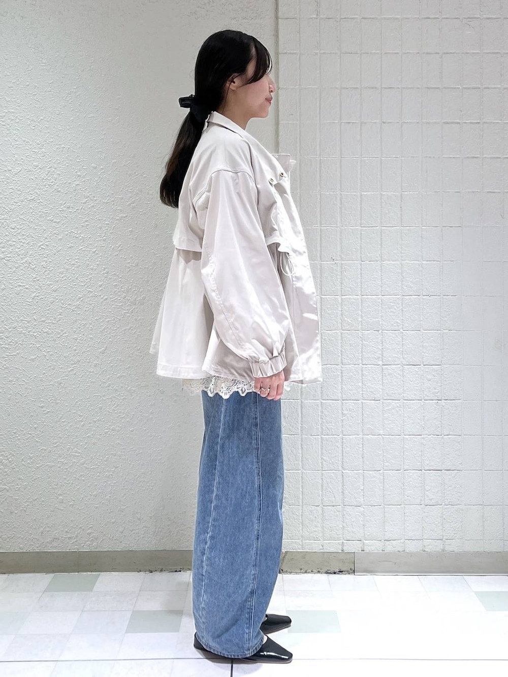 ブルー系のデニムパンツ、ベージュ系のブルゾン、ホワイト系のキャミソールを着用したレディースの春コーディネートの3枚目の写真