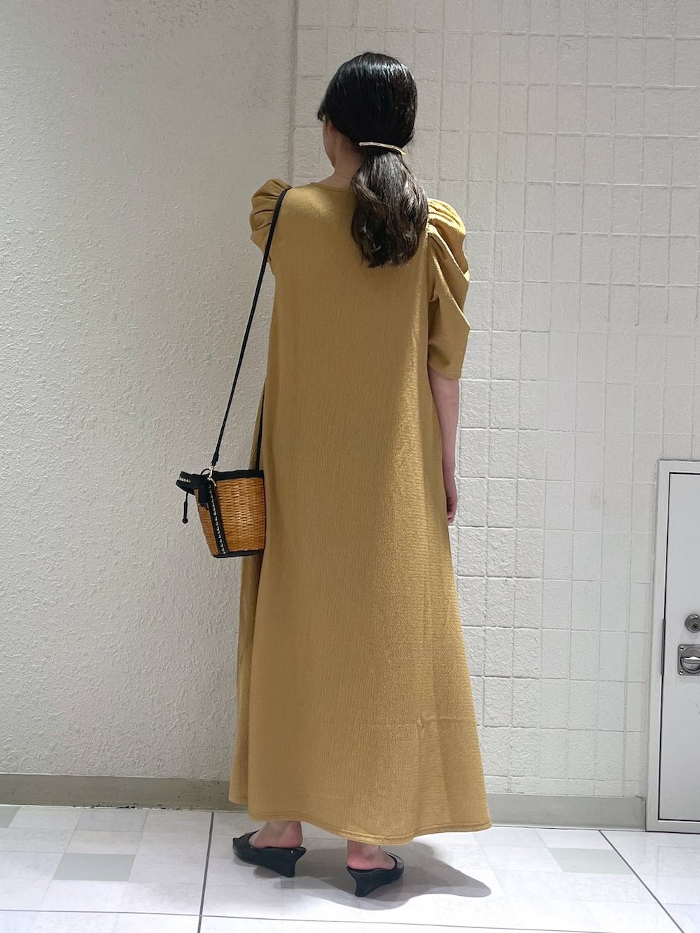 ブラック系のサンダル、ブラック系のショルダーバッグ、オレンジ系のワンピースを着用したレディースの夏コーディネートの3枚目の写真