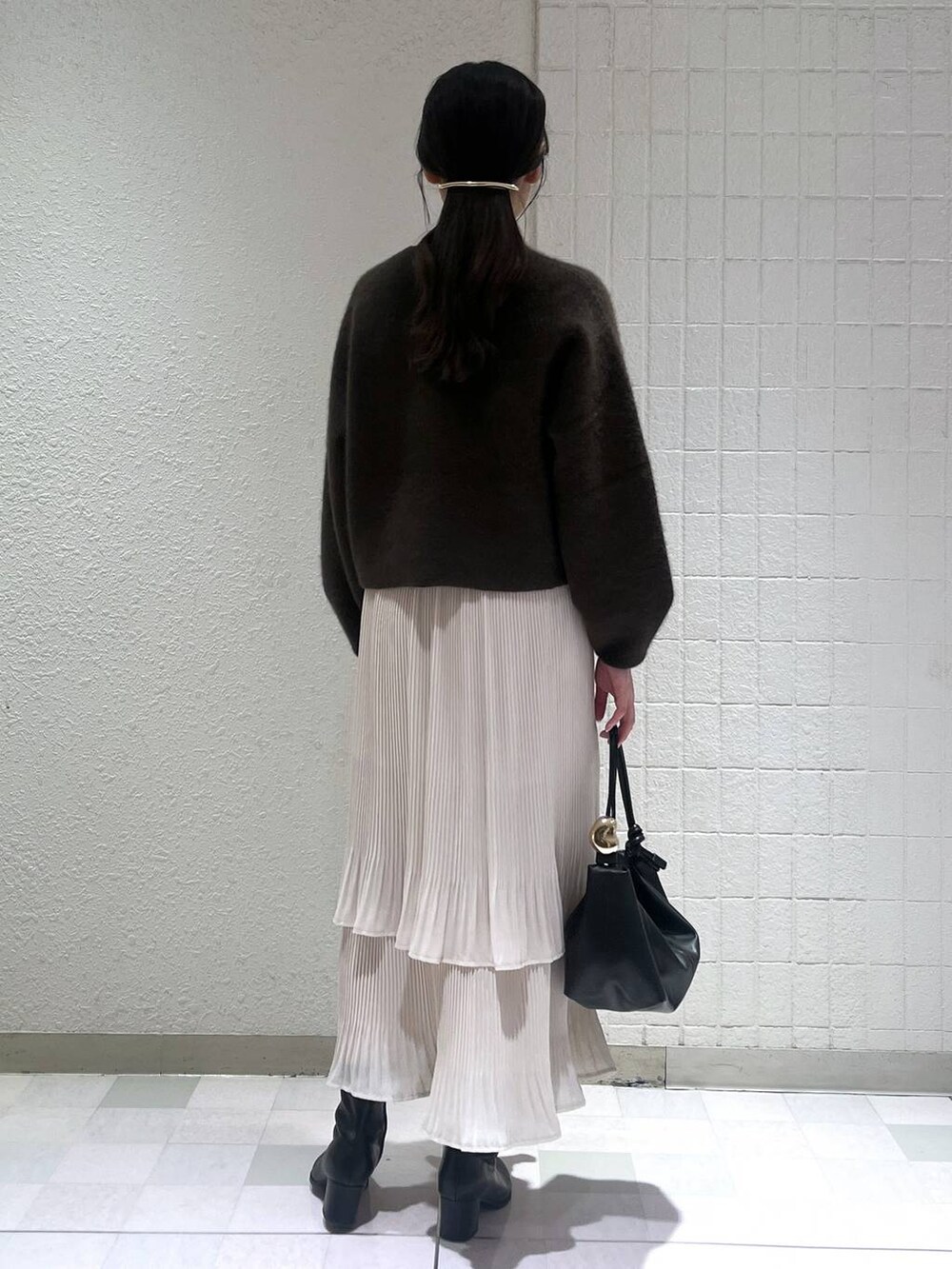 ブラック系のブーツ、ホワイト系のスカート、ブラウン系のカーディガン/ボレロを着用したレディースの秋コーディネートの3枚目の写真
