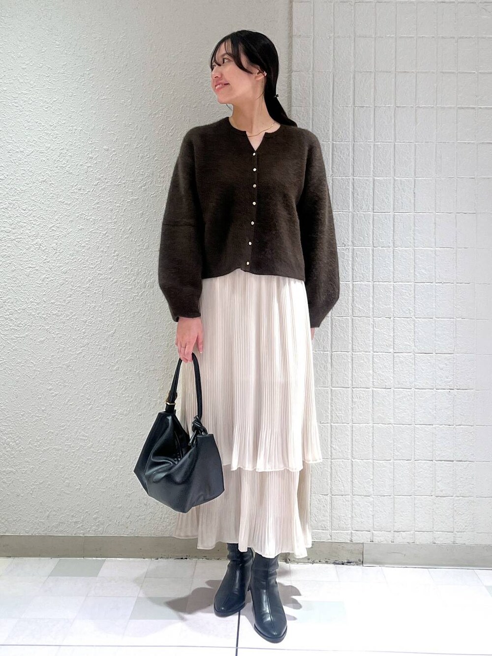 ブラック系のブーツ、ホワイト系のスカート、ブラウン系のカーディガン/ボレロを着用したレディースの秋コーディネートの4枚目の写真