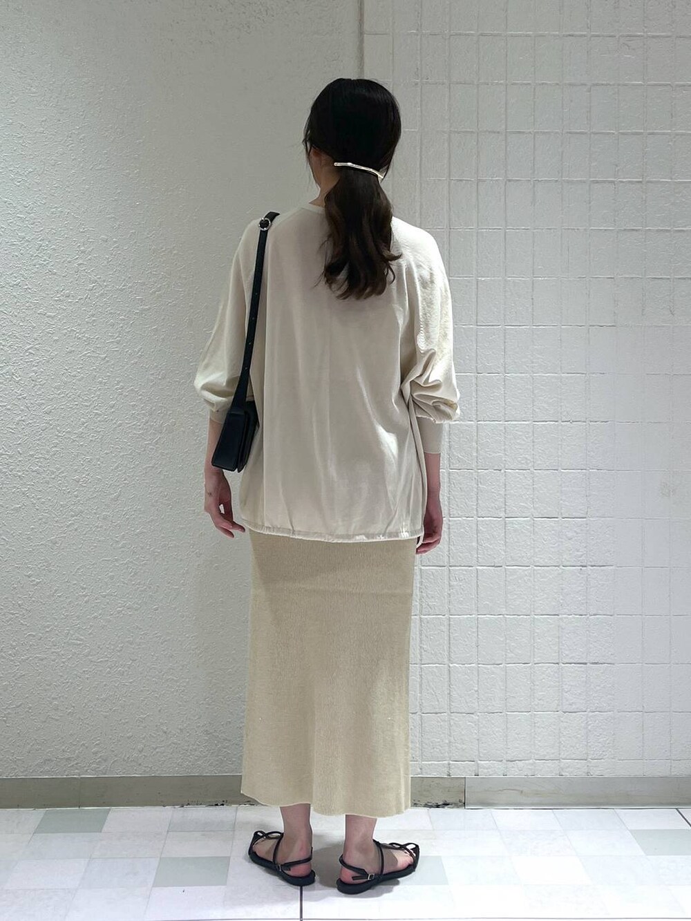 ゴールド系のスカート、ブラック系のサンダル、ホワイト系のタンクトップを着用したレディースの夏コーディネートの3枚目の写真