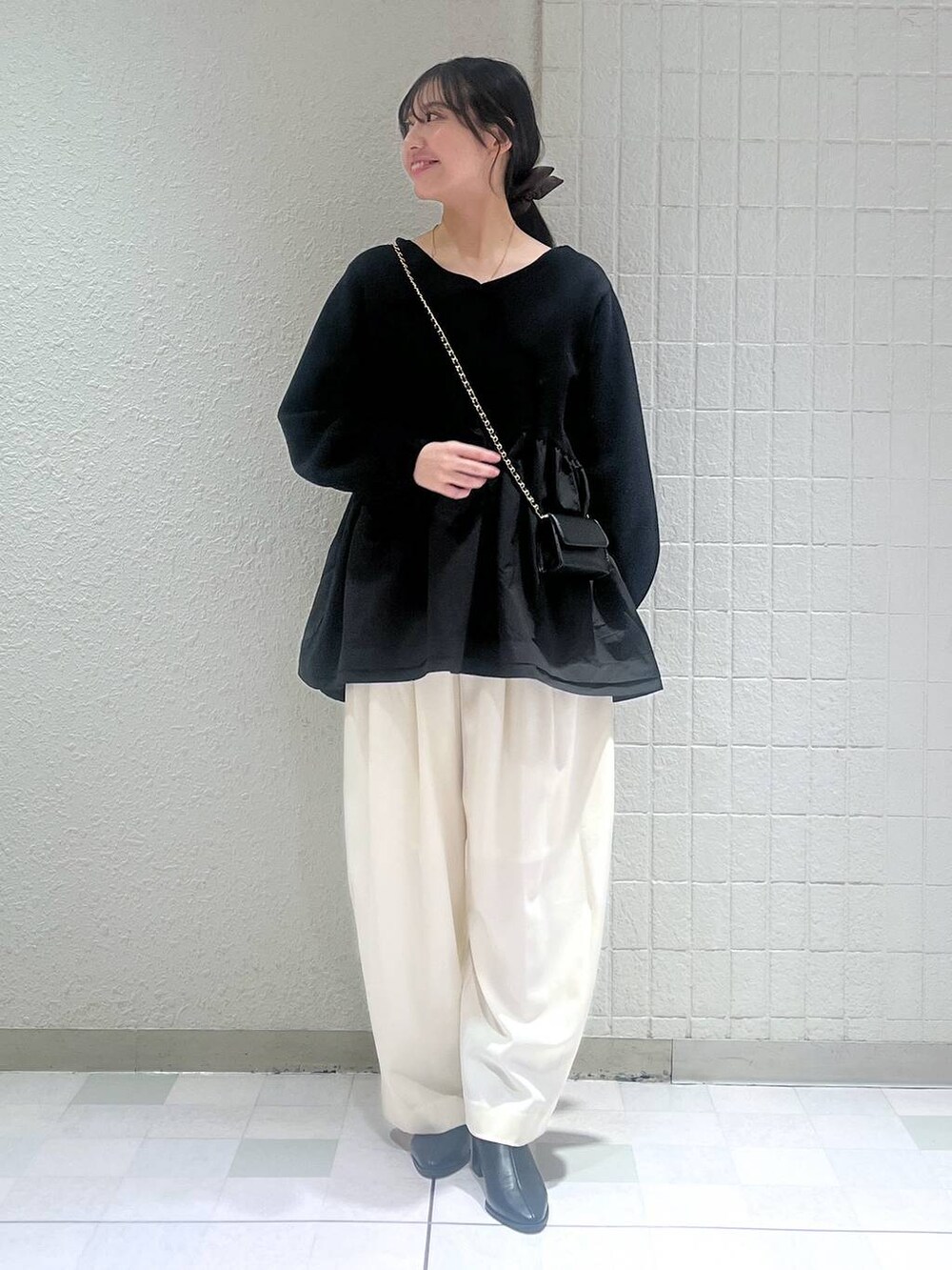 グレー系のステンカラーコート、ホワイト系のスラックス、ブラック系のブーツを着用したレディースの秋コーディネートの2枚目の写真