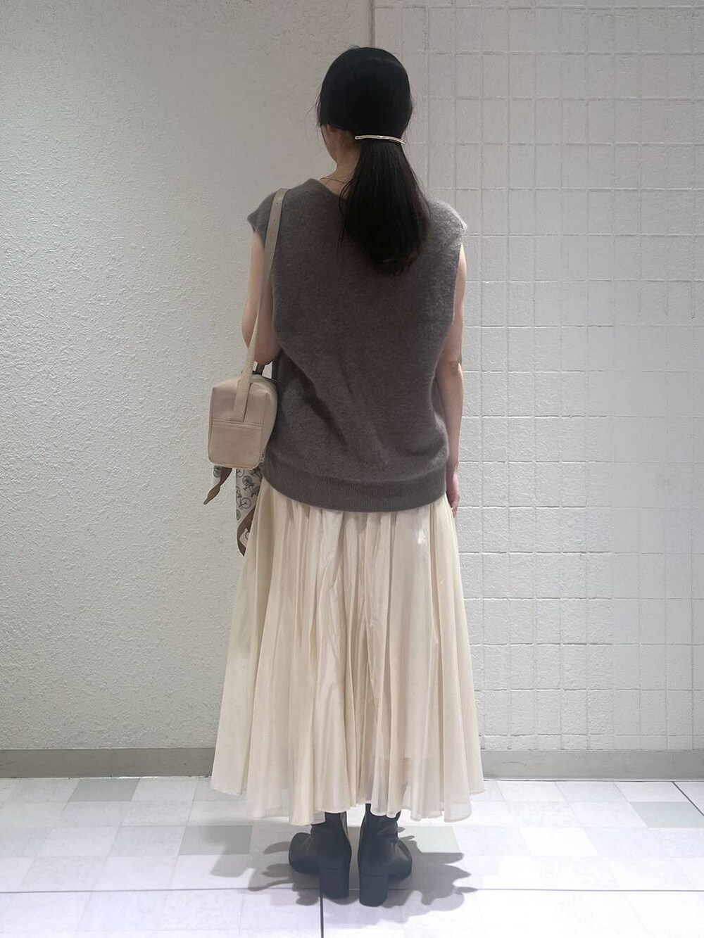 ブラック系のブーツ、ブラウン系のベスト、ホワイト系のスカートを着用したレディースの秋コーディネートの3枚目の写真