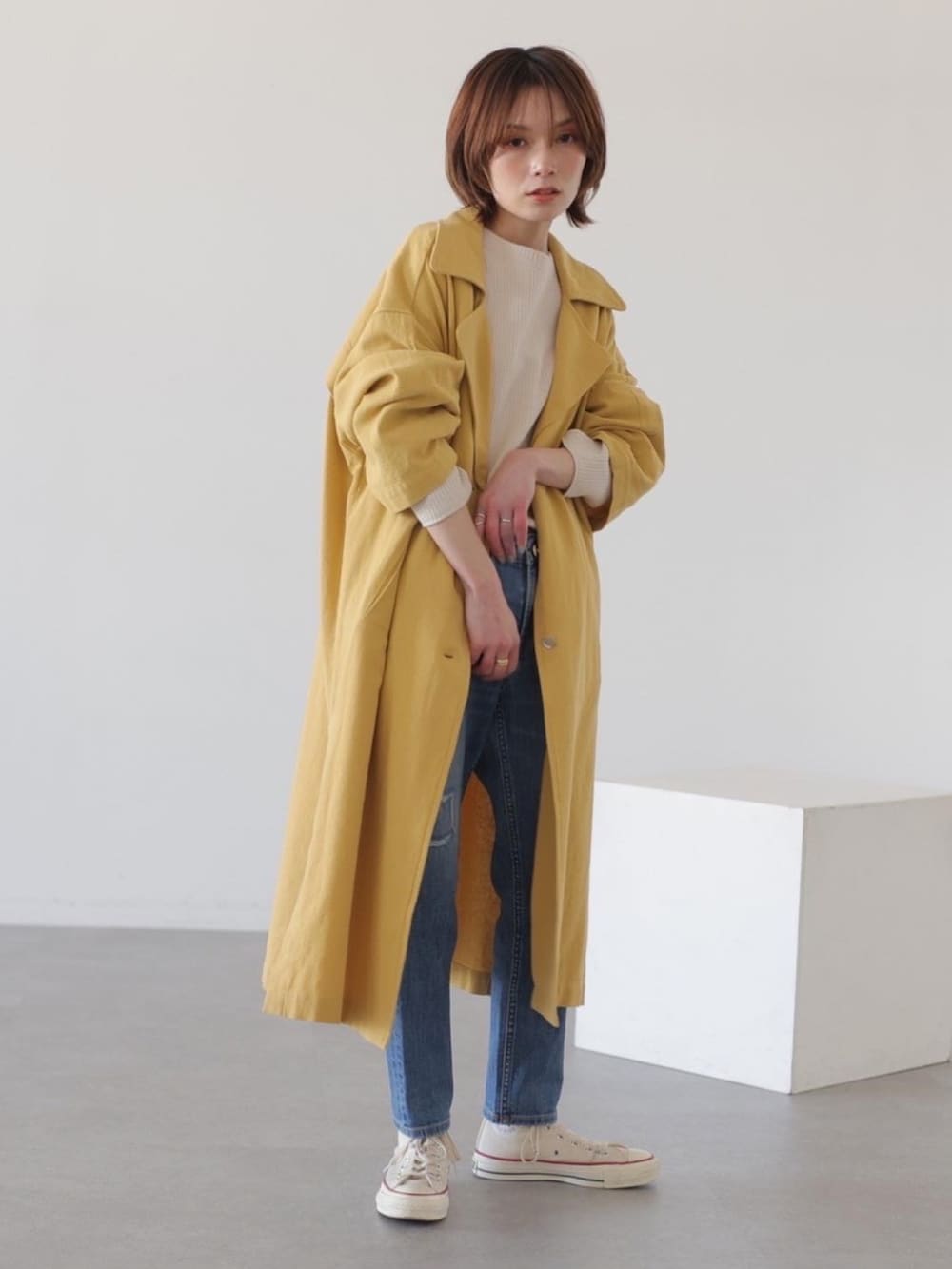 ブルー系のデニムパンツ、イエロー系のチェスターコート、ホワイト系のTシャツ/カットソーを着用したレディースの冬コーディネートの4枚目の写真