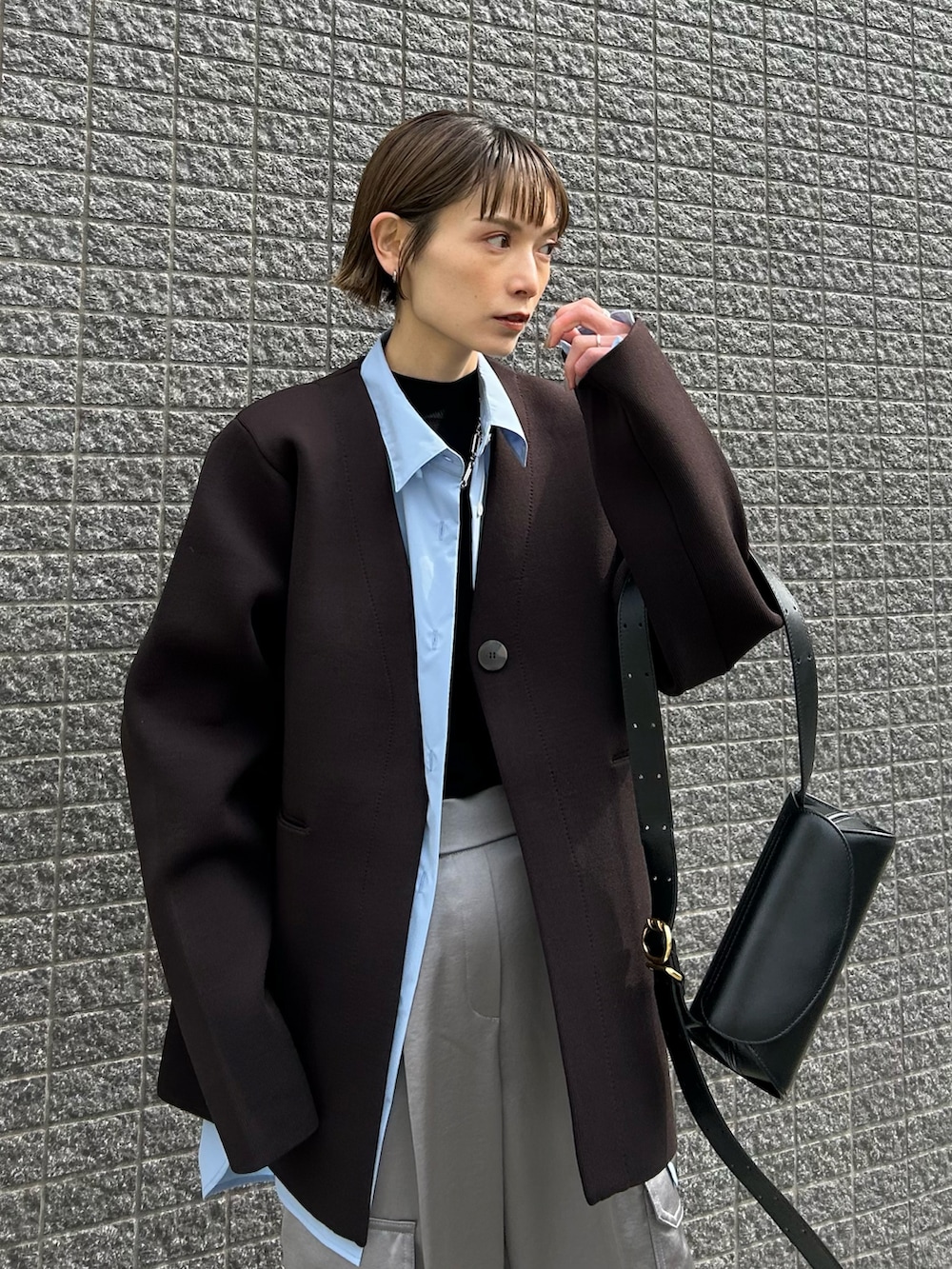 ブラウン系のその他アウター、ブラック系のショルダーバッグ、グレー系のスニーカーを着用したレディースの冬コーディネートの2枚目の写真