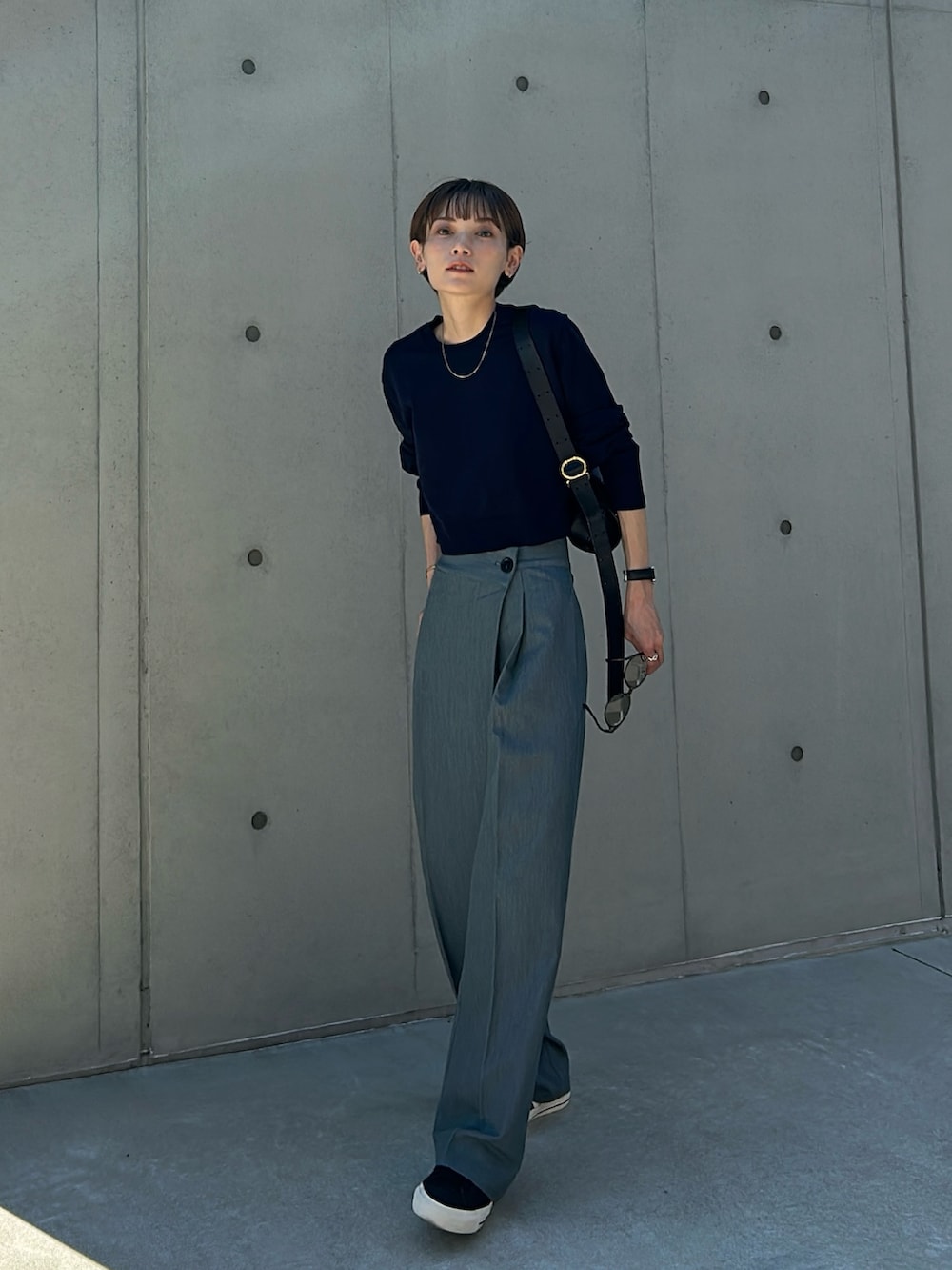 グレー系のスラックス、ブルー系のニット/セーター、ブラック系のショルダーバッグを着用したレディースの秋コーディネートの2枚目の写真