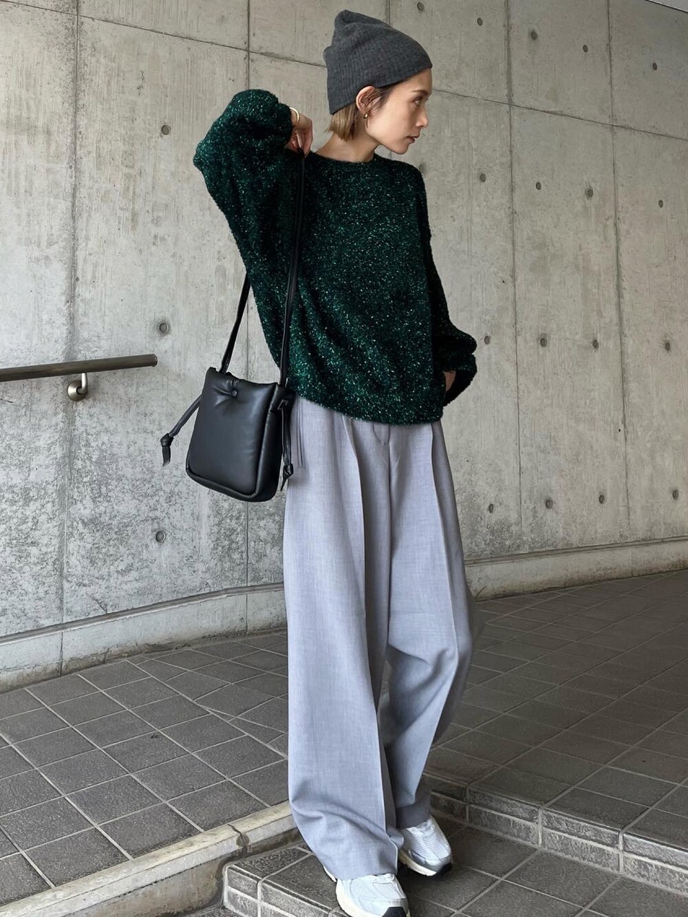 グリーン系のニット/セーター、グレー系のパンツ、シルバー系のスニーカーを着用したレディースの秋コーディネートの3枚目の写真