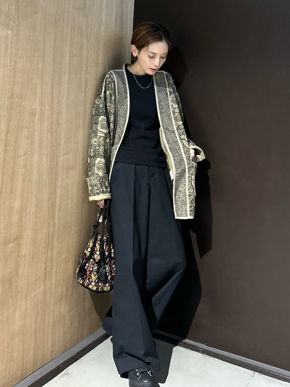 ブラック系のハンドバッグ、ブラック系のスニーカーを着用したレディースの秋コーディネートの3枚目の写真