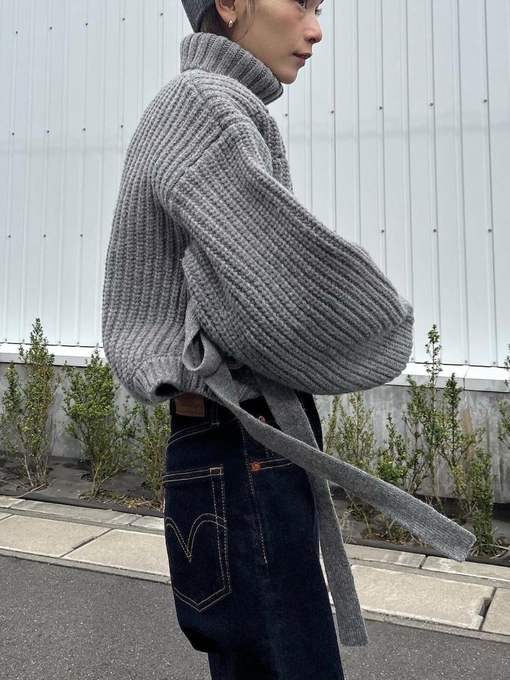 グレー系のニット/セーター、ブルー系のデニムパンツ、レッド系のスニーカーを着用したレディースの秋コーディネートの5枚目の写真