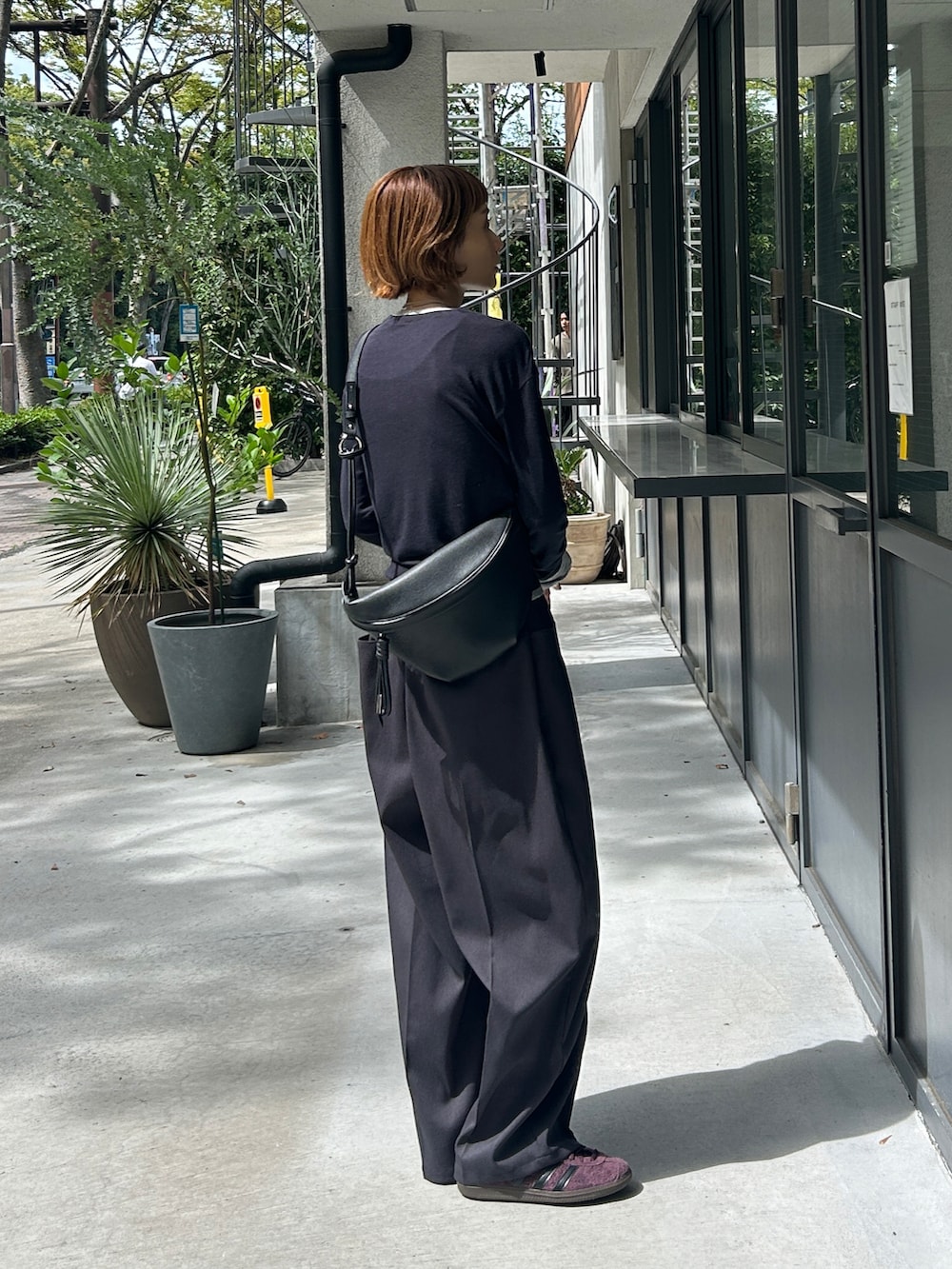 グレー系のパンツ、ブルー系のトップス、ブラック系のクラッチバッグを着用したレディースの秋コーディネートの3枚目の写真