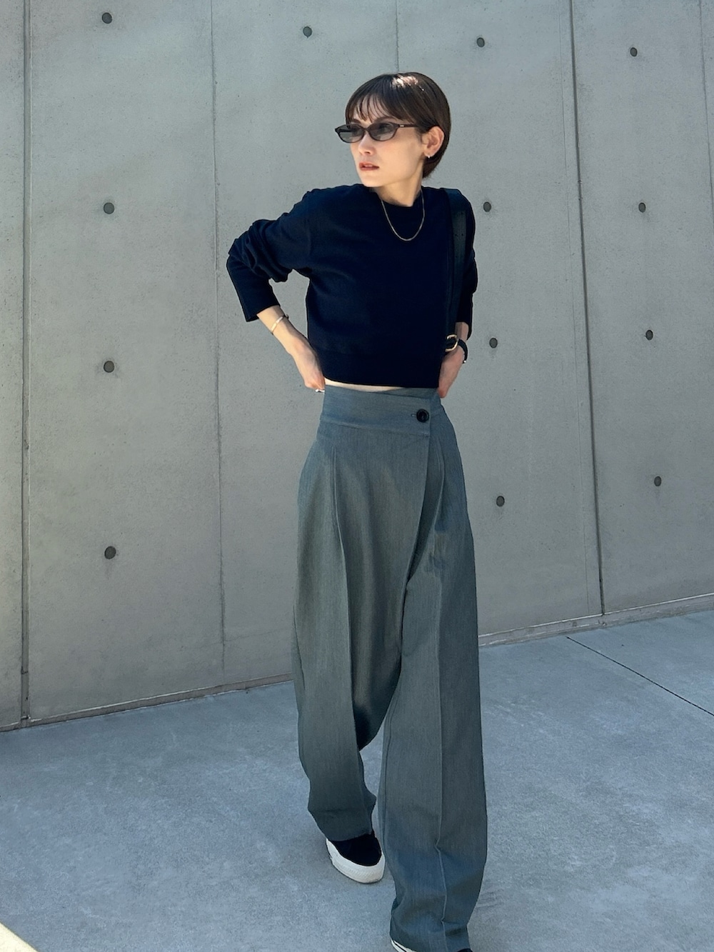 グレー系のスラックス、ブルー系のニット/セーター、ブラック系のショルダーバッグを着用したレディースの秋コーディネートの3枚目の写真