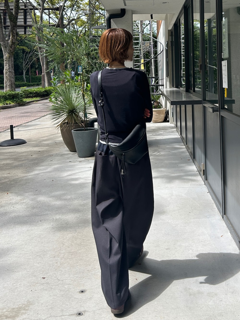 グレー系のパンツ、ブルー系のトップス、ブラック系のクラッチバッグを着用したレディースの秋コーディネートの2枚目の写真