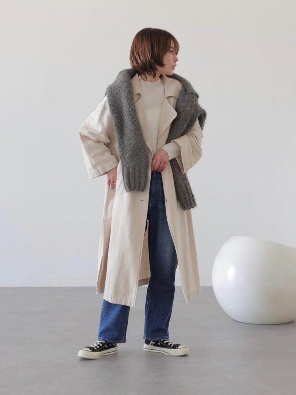 ブルー系のデニムパンツ、ベージュ系のチェスターコート、グレー系のニット/セーターを着用したレディースの冬コーディネートの2枚目の写真