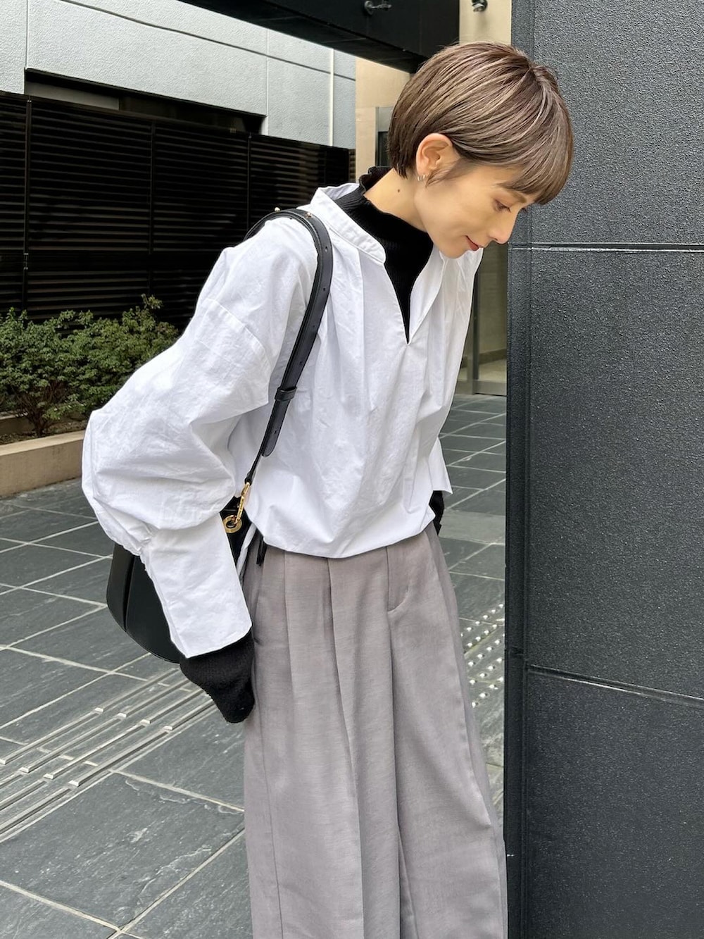 グレー系のスニーカー、ブラック系のニット/セーター、ホワイト系のシャツ/ブラウスを着用したレディースの春コーディネートの3枚目の写真