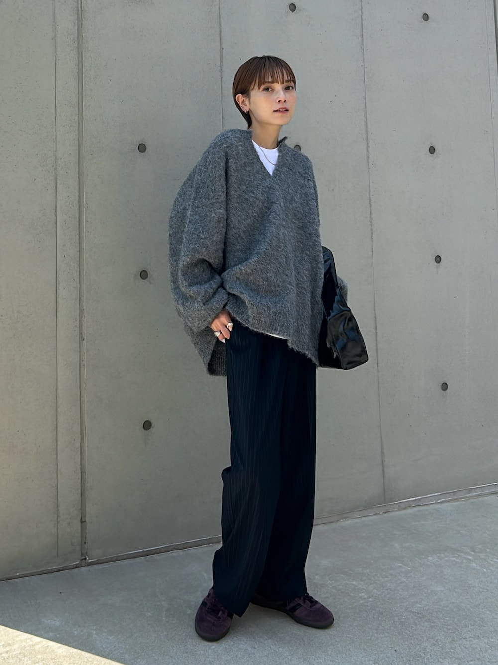 グレー系のニット/セーター、レッド系のスニーカー、ブラック系のバッグを着用したレディースの秋コーディネートの2枚目の写真