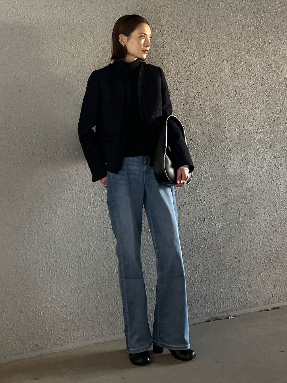 ブルー系のデニムパンツ、ブルー系のノーカラージャケット、ブラック系のショルダーバッグを着用したレディースの冬コーディネートの3枚目の写真