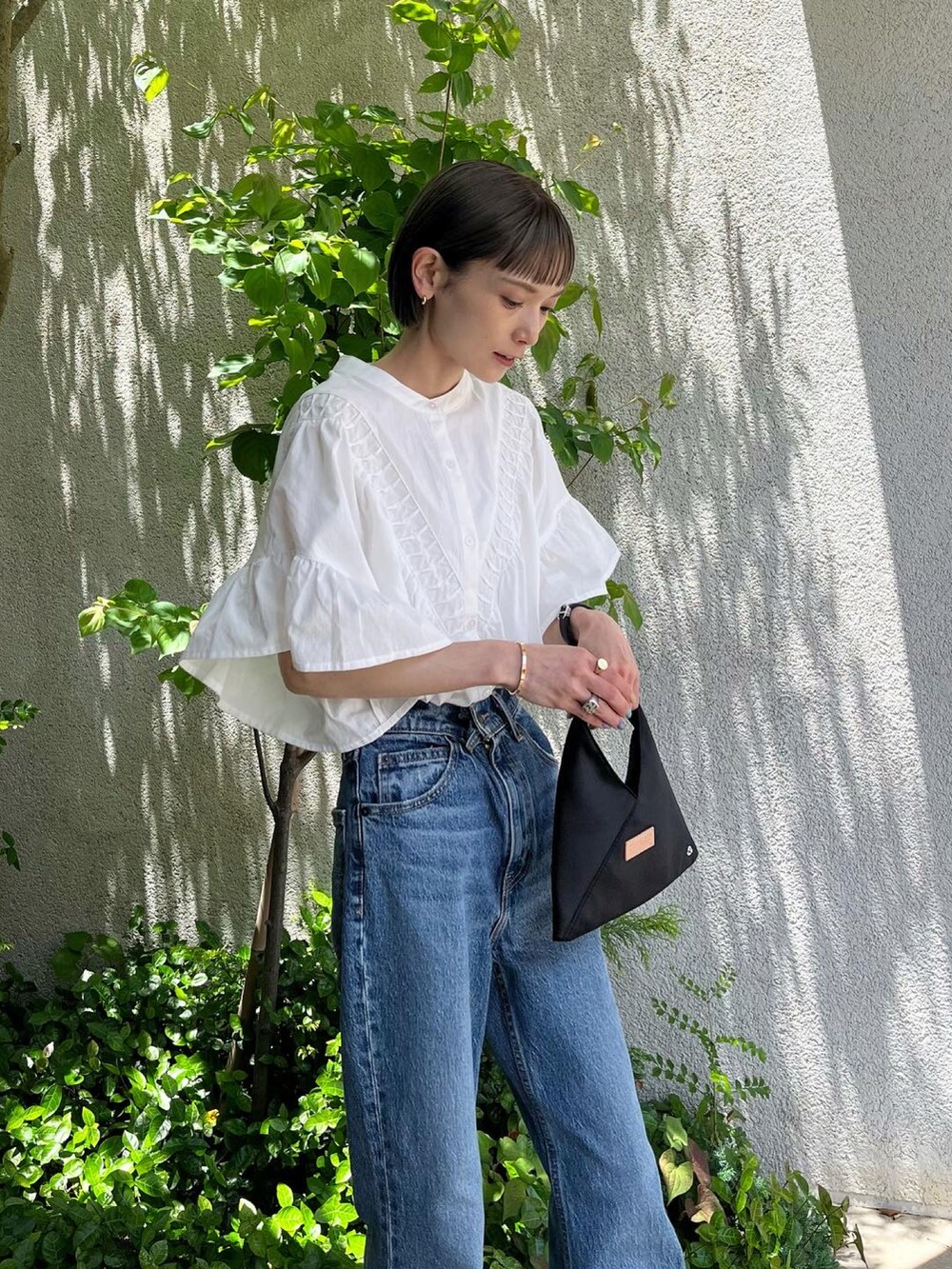 ブルー系のデニムパンツ、ホワイト系のシャツ/ブラウス、その他のショルダーバッグを着用したレディースの夏コーディネートの2枚目の写真