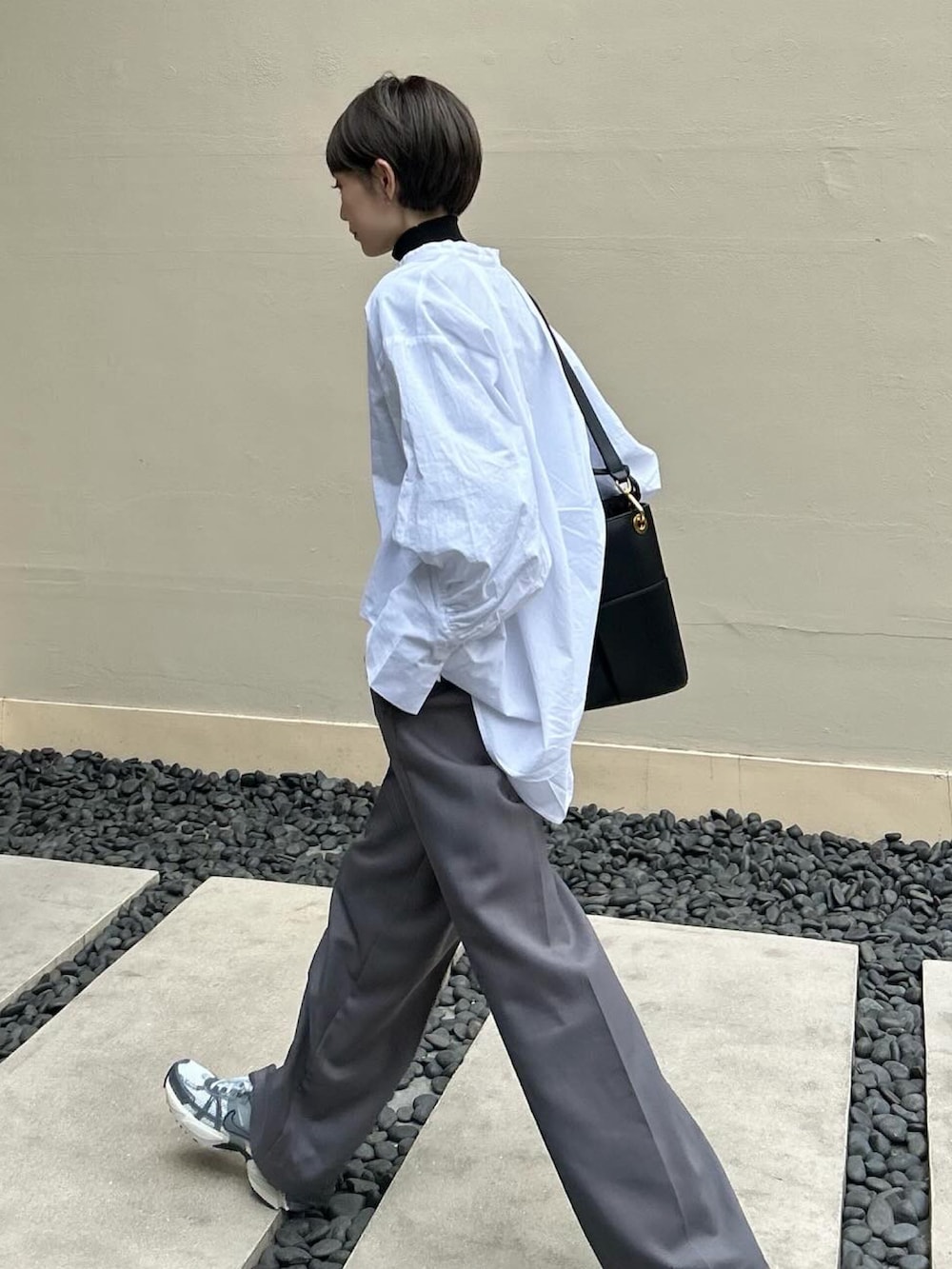 グレー系のスニーカー、ブラック系のニット/セーター、ホワイト系のシャツ/ブラウスを着用したレディースの春コーディネートの2枚目の写真