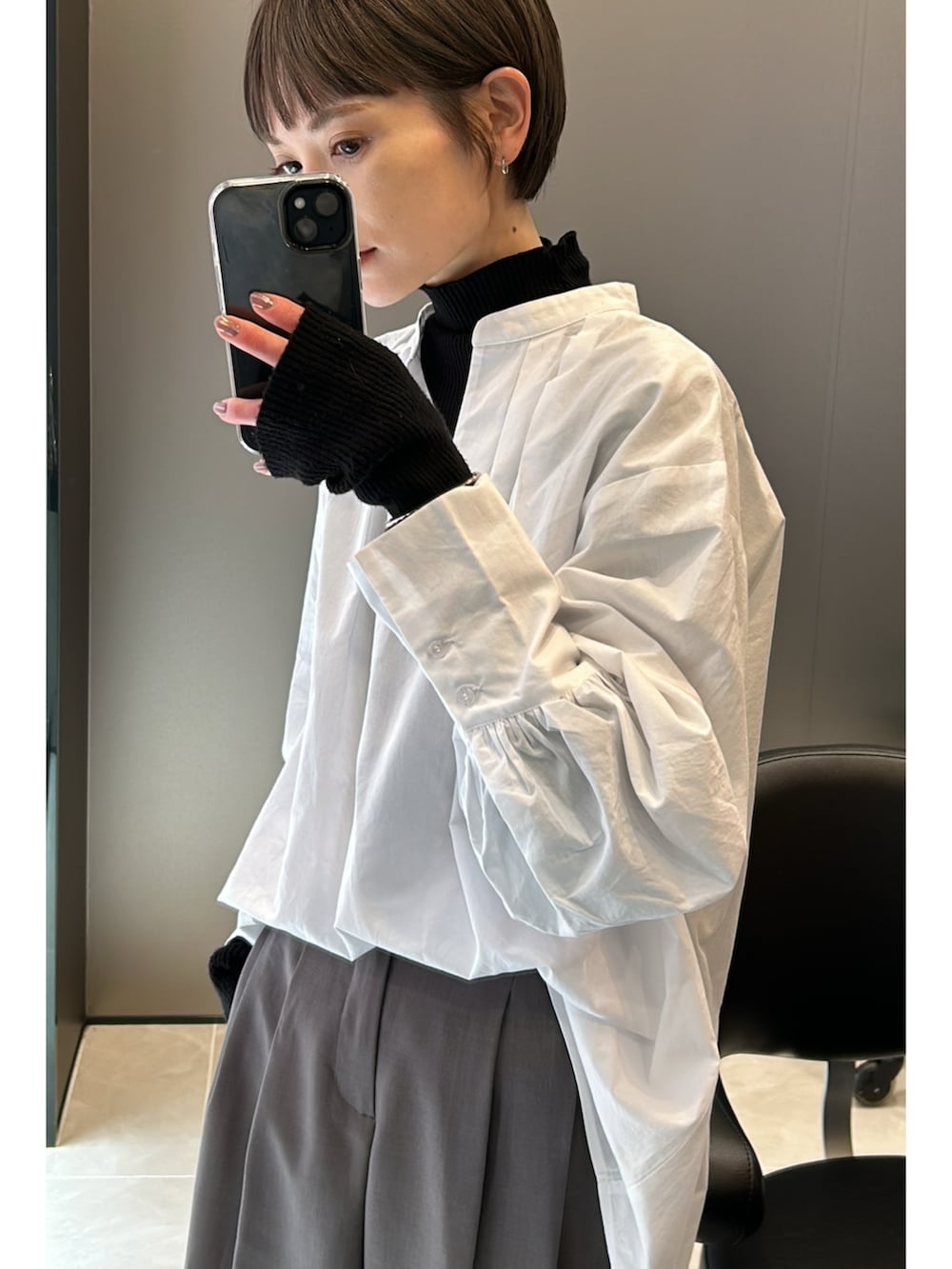 グレー系のスニーカー、ブラック系のニット/セーター、ホワイト系のシャツ/ブラウスを着用したレディースの春コーディネートの5枚目の写真