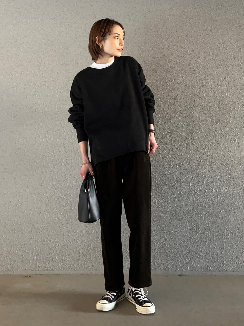 ブラック系のスウェット、ホワイト系のその他パンツ、ブラック系のハンドバッグを着用したレディースの冬コーディネートの2枚目の写真