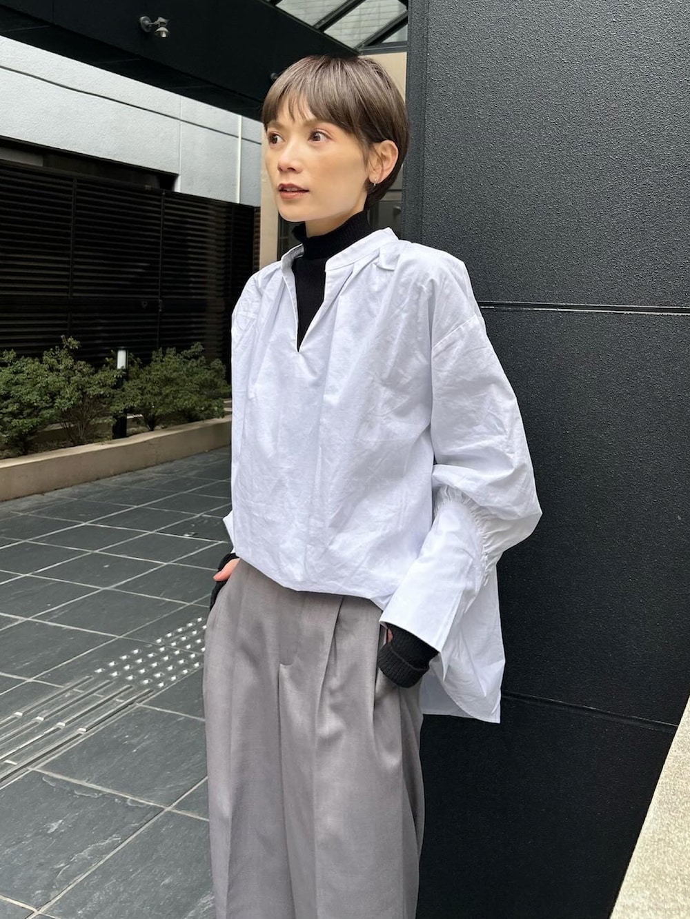 グレー系のスニーカー、ブラック系のニット/セーター、ホワイト系のシャツ/ブラウスを着用したレディースの春コーディネートの4枚目の写真