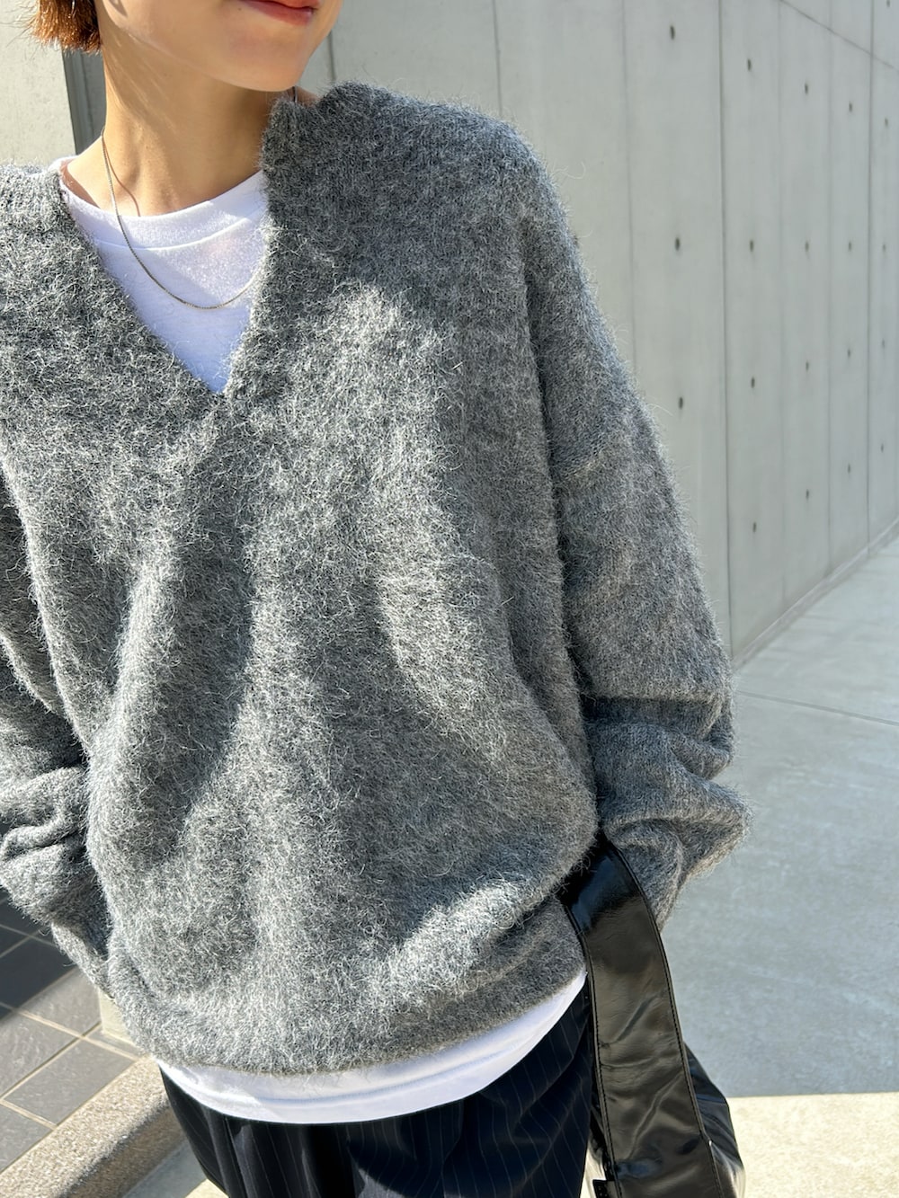 グレー系のニット/セーター、レッド系のスニーカー、ブラック系のバッグを着用したレディースの秋コーディネートの3枚目の写真