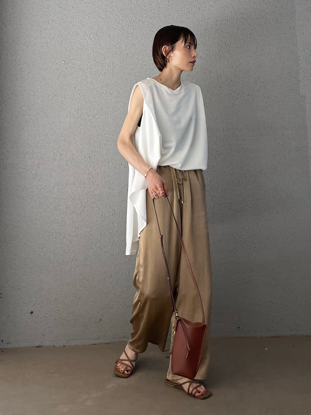 ベージュ系のその他パンツ、ホワイト系のTシャツ/カットソー、ブラウン系のサンダルを着用したレディースの夏コーディネートの2枚目の写真