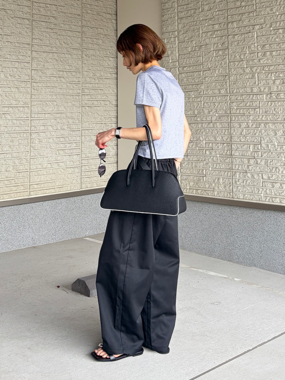 ブラック系のボストンバッグ、グレー系のTシャツ/カットソー、ブラック系のチノパンツを着用したレディースの夏コーディネートの2枚目の写真
