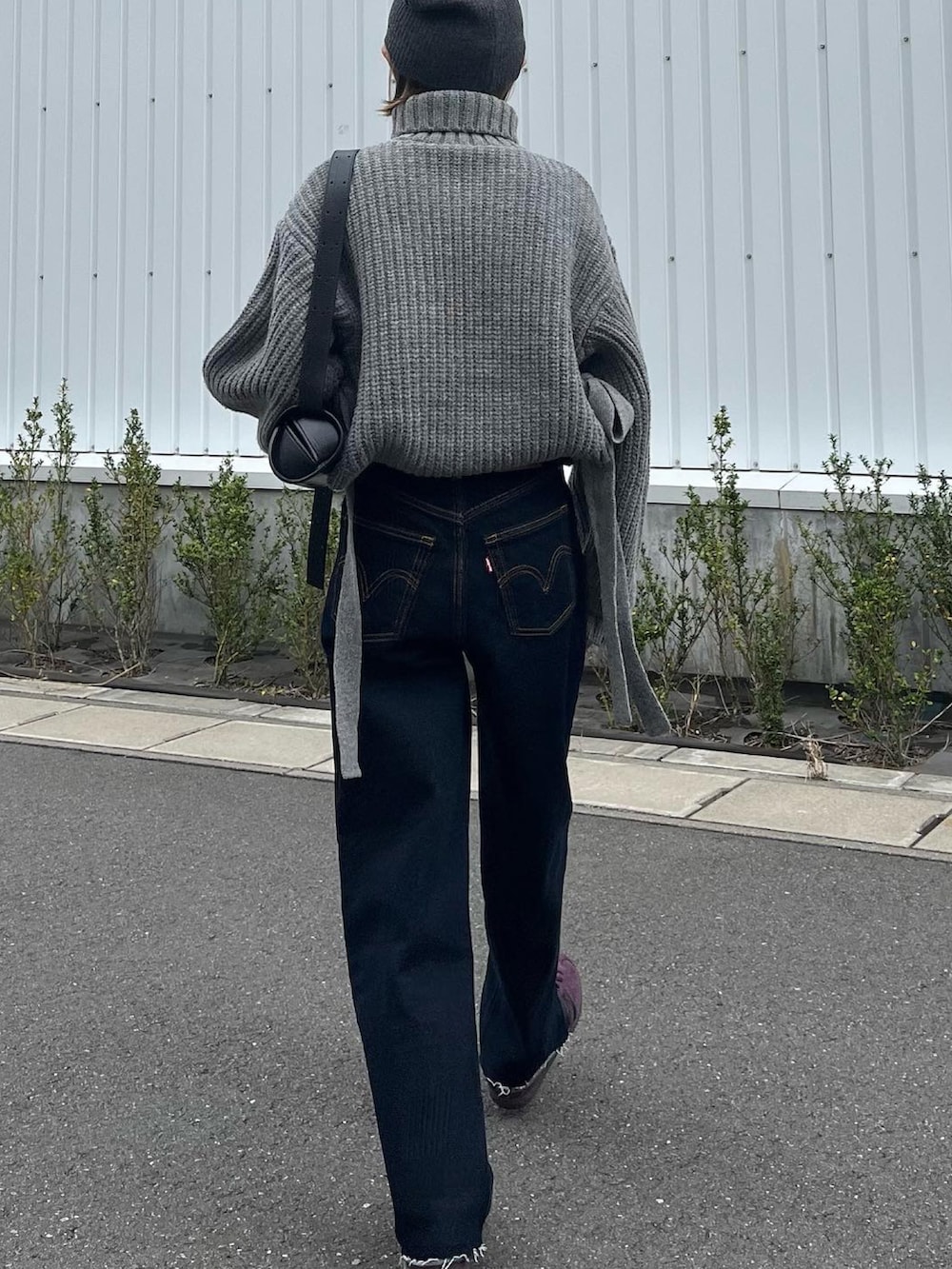 グレー系のニット/セーター、ブルー系のデニムパンツ、レッド系のスニーカーを着用したレディースの秋コーディネートの4枚目の写真