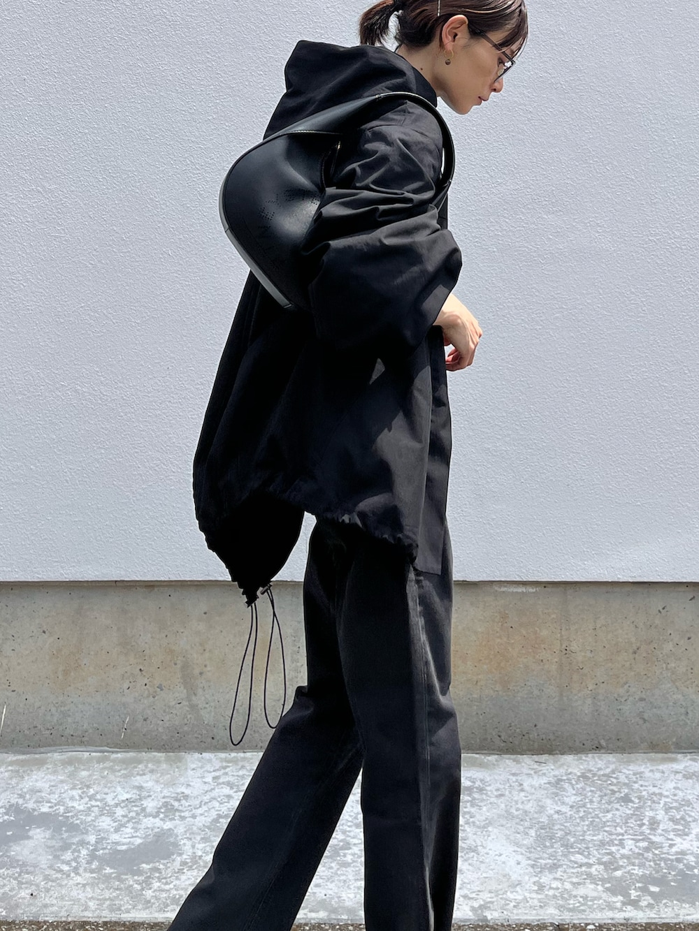 ブラック系のデニムパンツ、ブラック系のブルゾン、ブラック系のショルダーバッグを着用したレディースの夏コーディネートの4枚目の写真