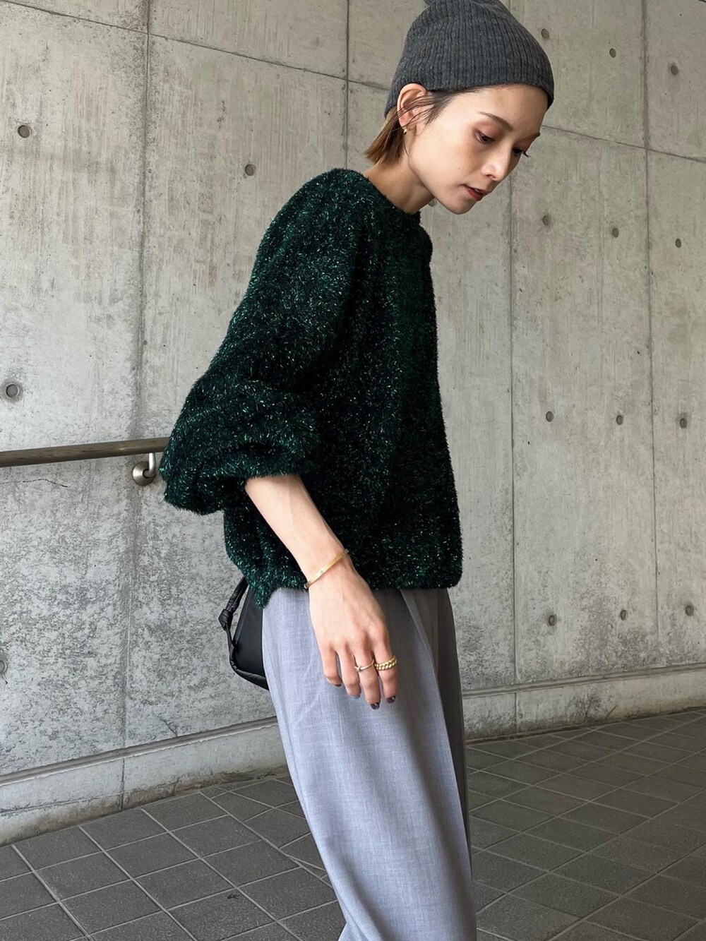 グリーン系のニット/セーター、グレー系のパンツ、シルバー系のスニーカーを着用したレディースの秋コーディネートの4枚目の写真