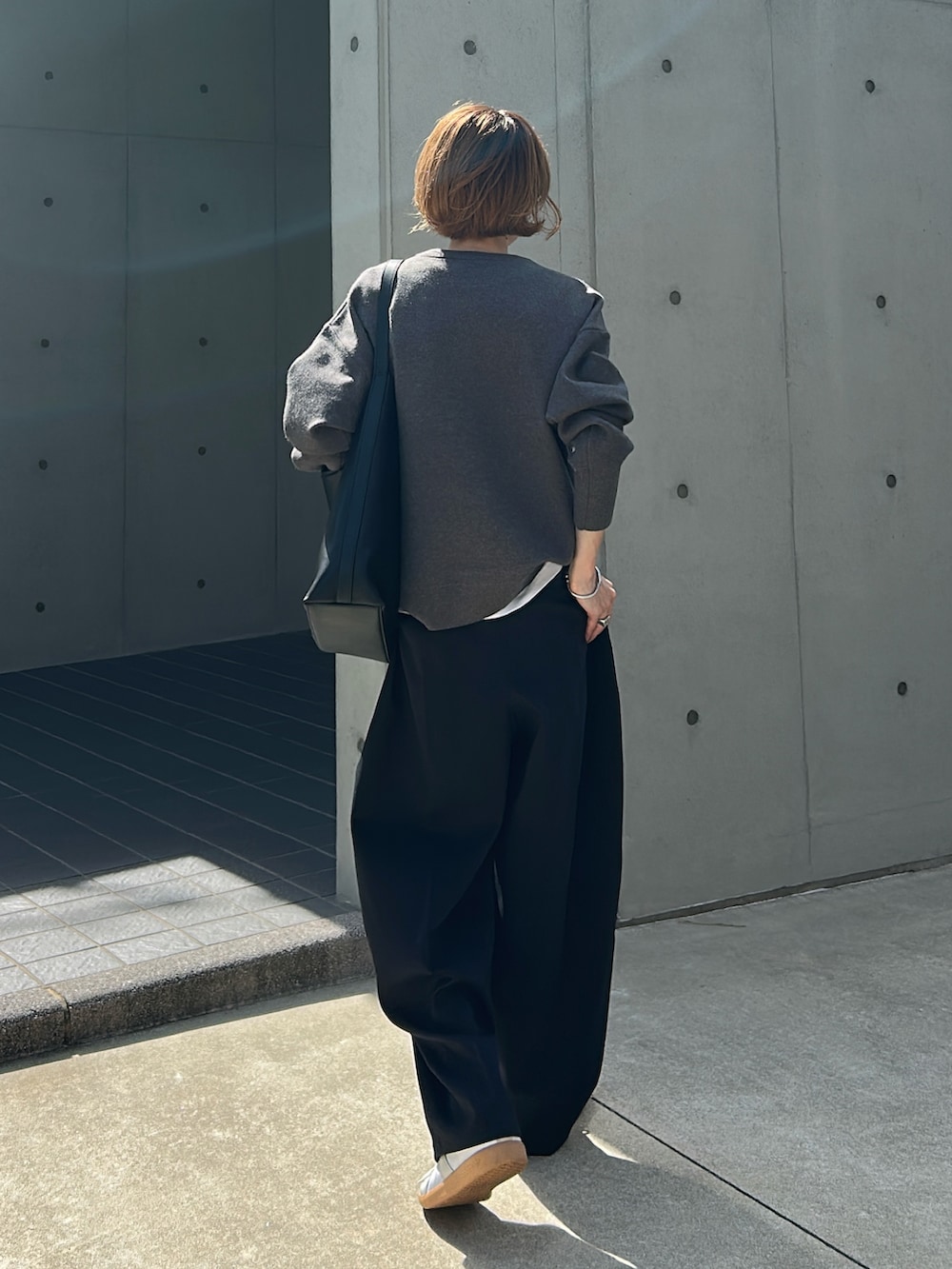 グレー系のニット/セーター、グレー系のパンツ、ブラック系のバッグを着用したレディースの秋コーディネートの3枚目の写真