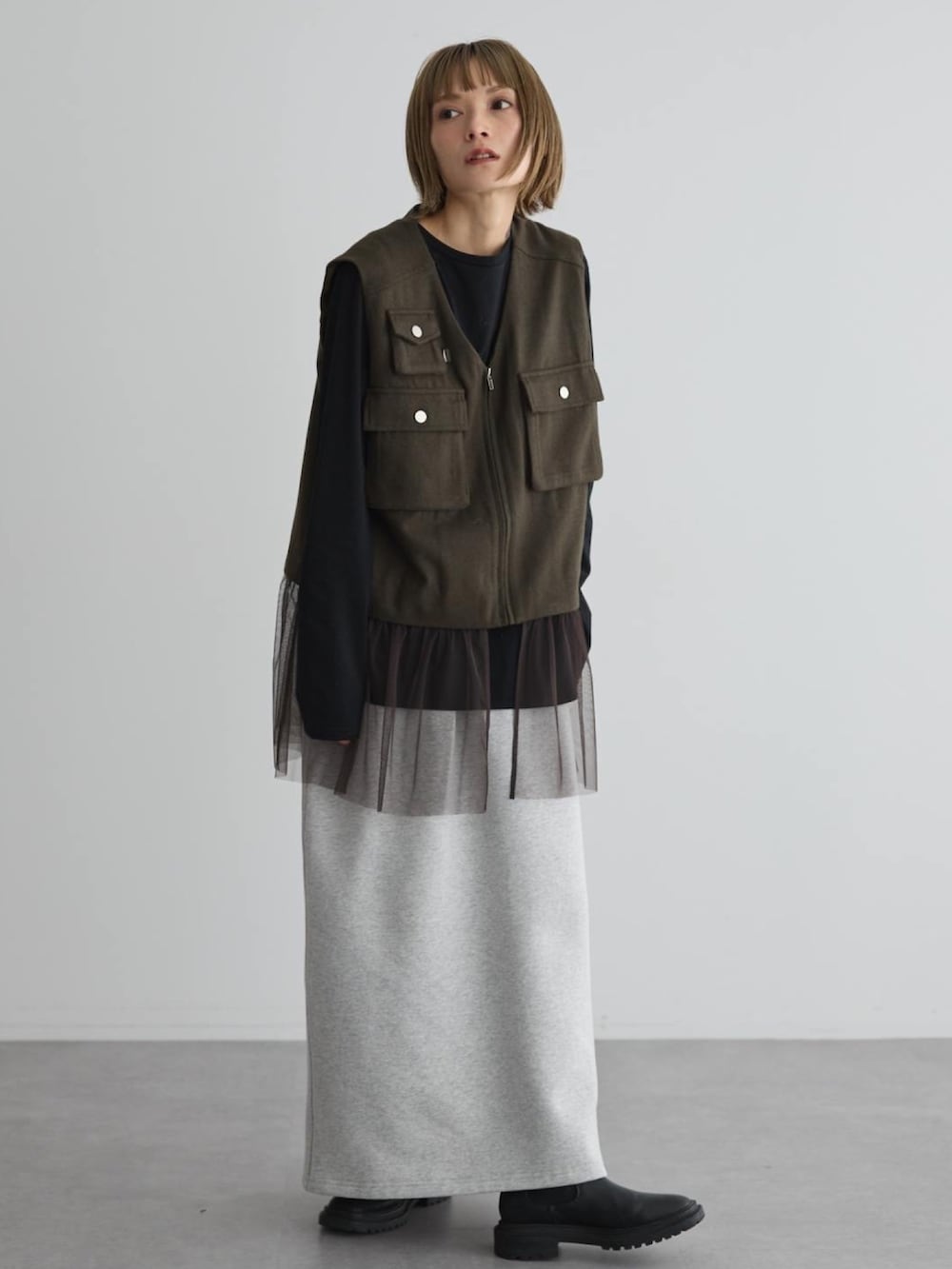 グリーン系のベスト、ブラック系のブーツを着用したレディースの秋コーディネートの3枚目の写真