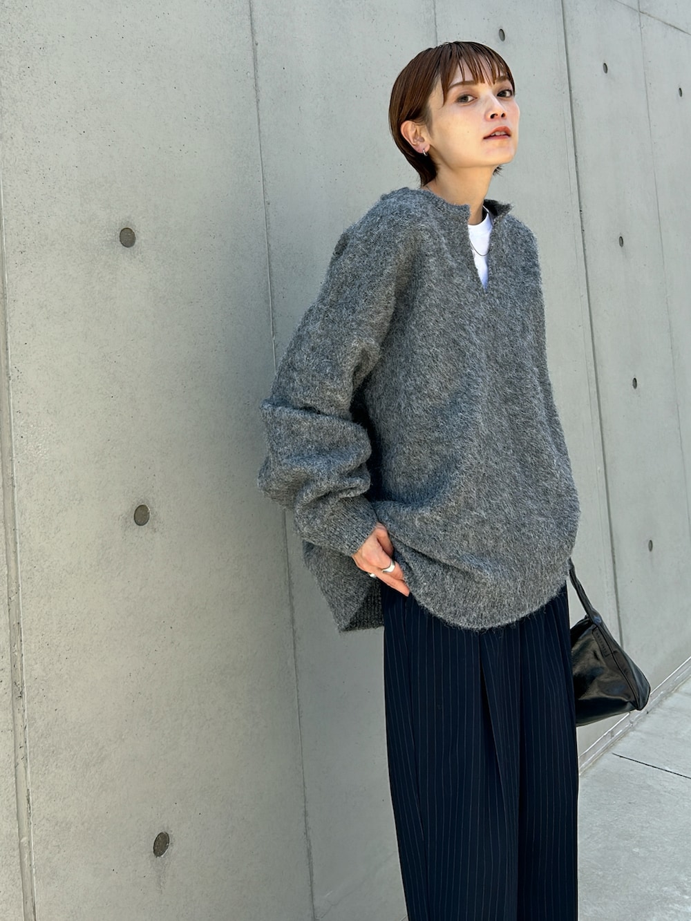 グレー系のニット/セーター、レッド系のスニーカー、ブラック系のバッグを着用したレディースの秋コーディネートの4枚目の写真