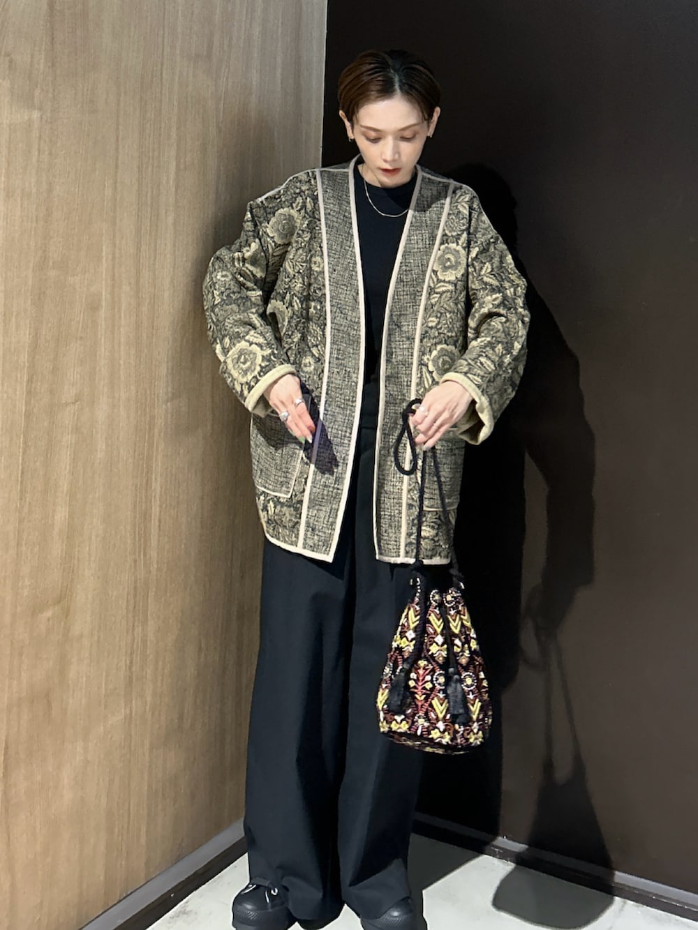 ブラック系のハンドバッグ、ブラック系のスニーカーを着用したレディースの秋コーディネートの2枚目の写真