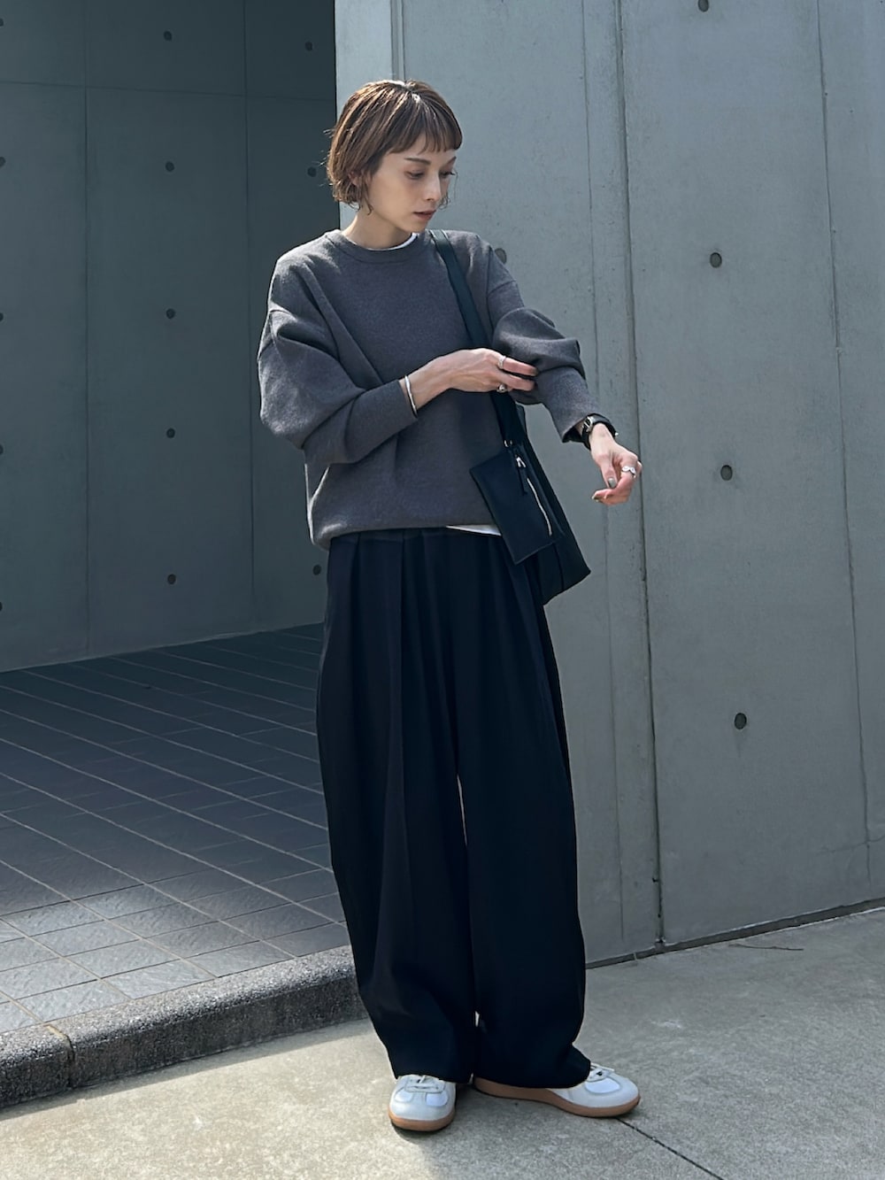 グレー系のニット/セーター、グレー系のパンツ、ブラック系のバッグを着用したレディースの秋コーディネートの4枚目の写真