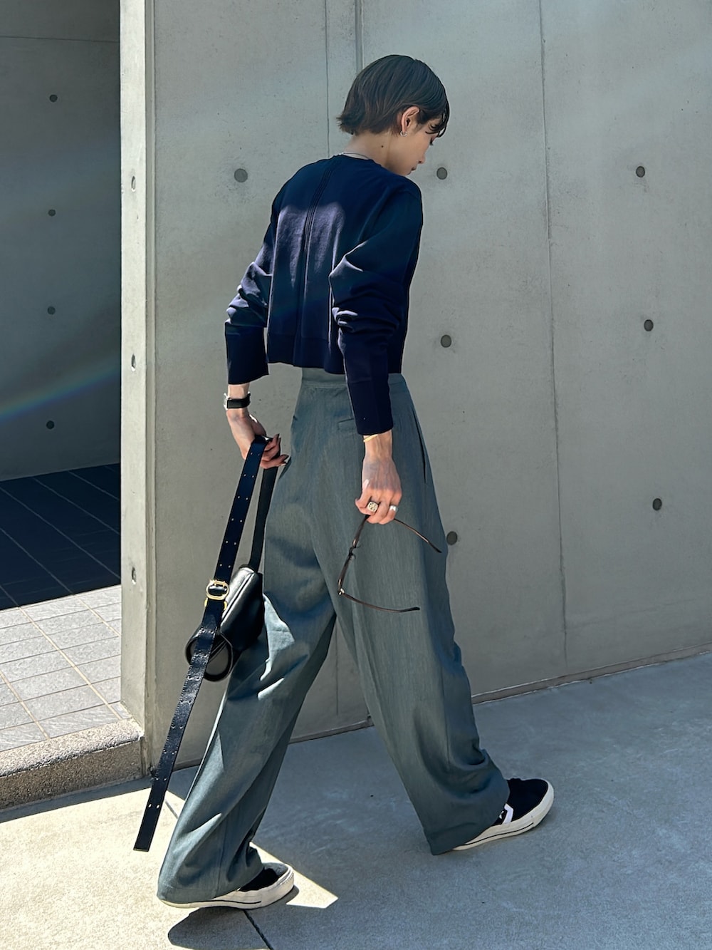 グレー系のスラックス、ブルー系のニット/セーター、ブラック系のショルダーバッグを着用したレディースの秋コーディネートの5枚目の写真