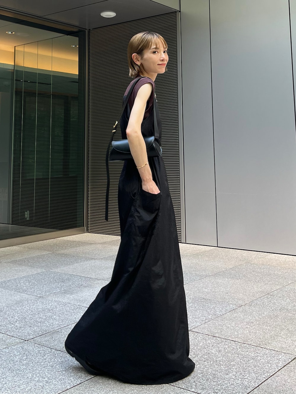 ブラック系のジャンパースカート、ブラック系のショルダーバッグ、ブラック系のサンダルを着用したレディースの夏コーディネートの2枚目の写真