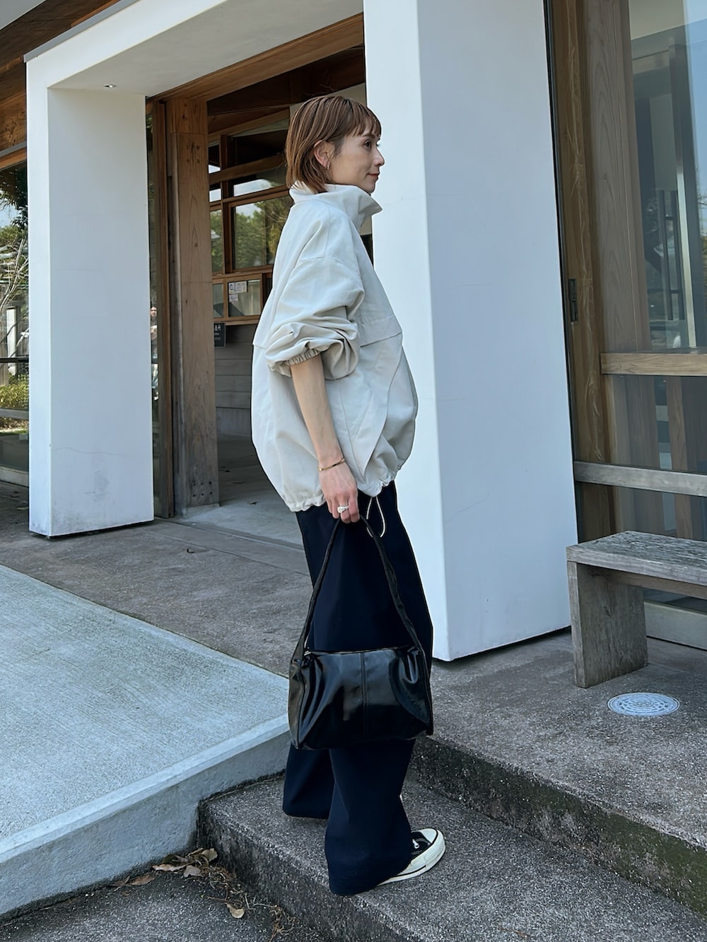 ホワイト系のブルゾン、ブルー系のパンツ、ブラック系のバッグを着用したレディースの春コーディネートの3枚目の写真