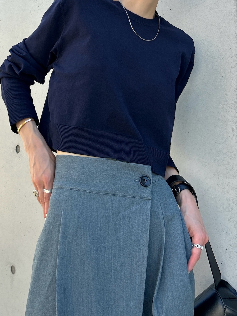 グレー系のスラックス、ブルー系のニット/セーター、ブラック系のショルダーバッグを着用したレディースの秋コーディネートの4枚目の写真