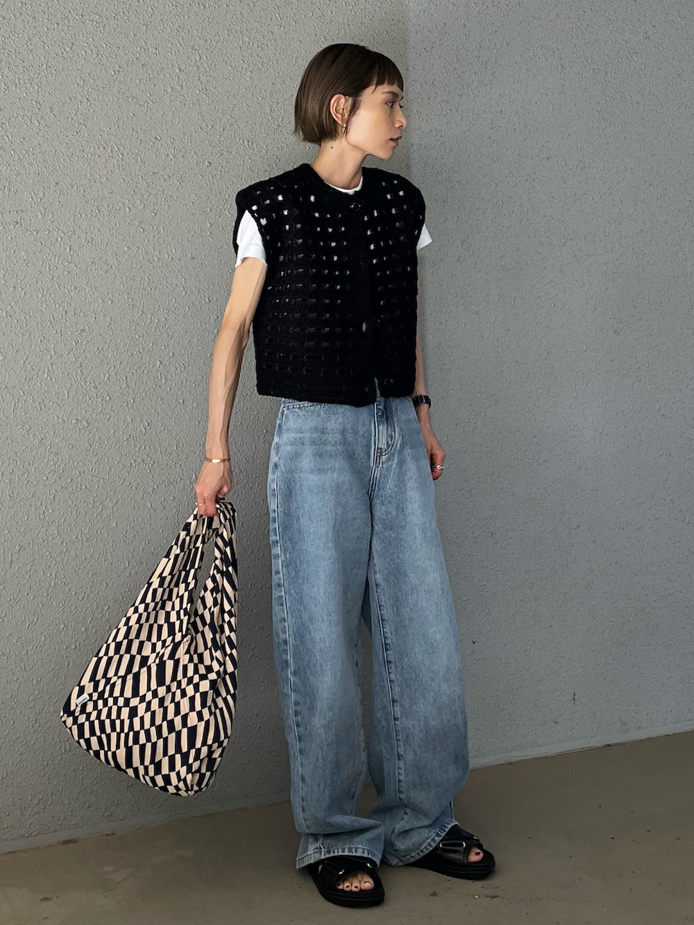 ブラック系のベスト、ブルー系のトートバッグ、ブラック系のサンダルを着用したレディースの夏コーディネートの2枚目の写真